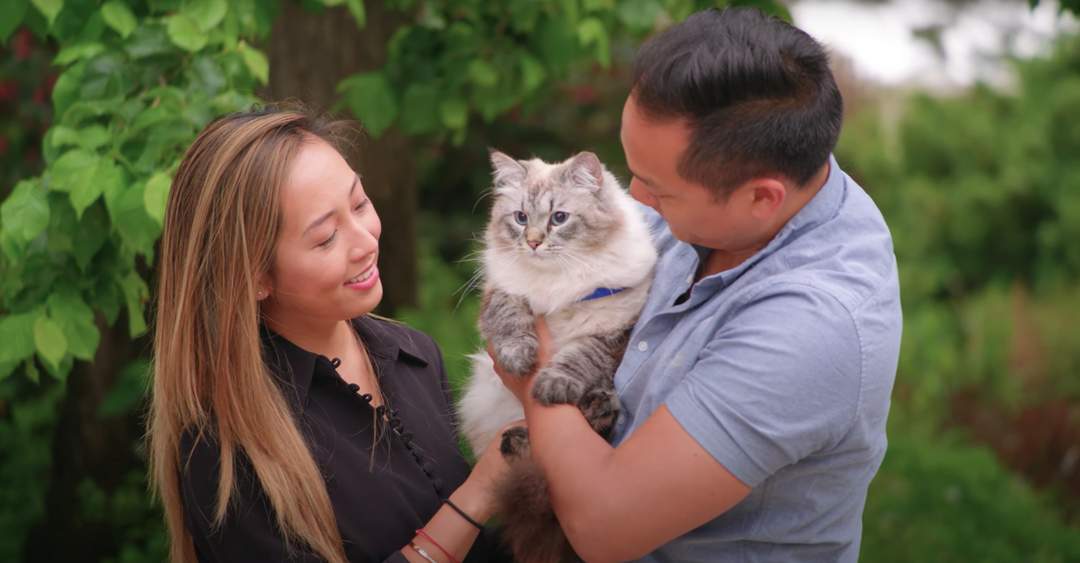 A man and woman holding their cat