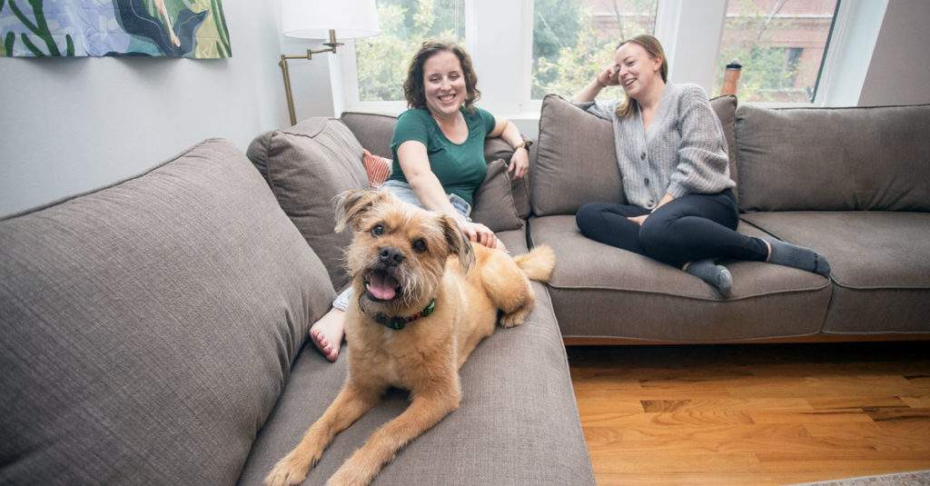two women and a dog sitting on a couch