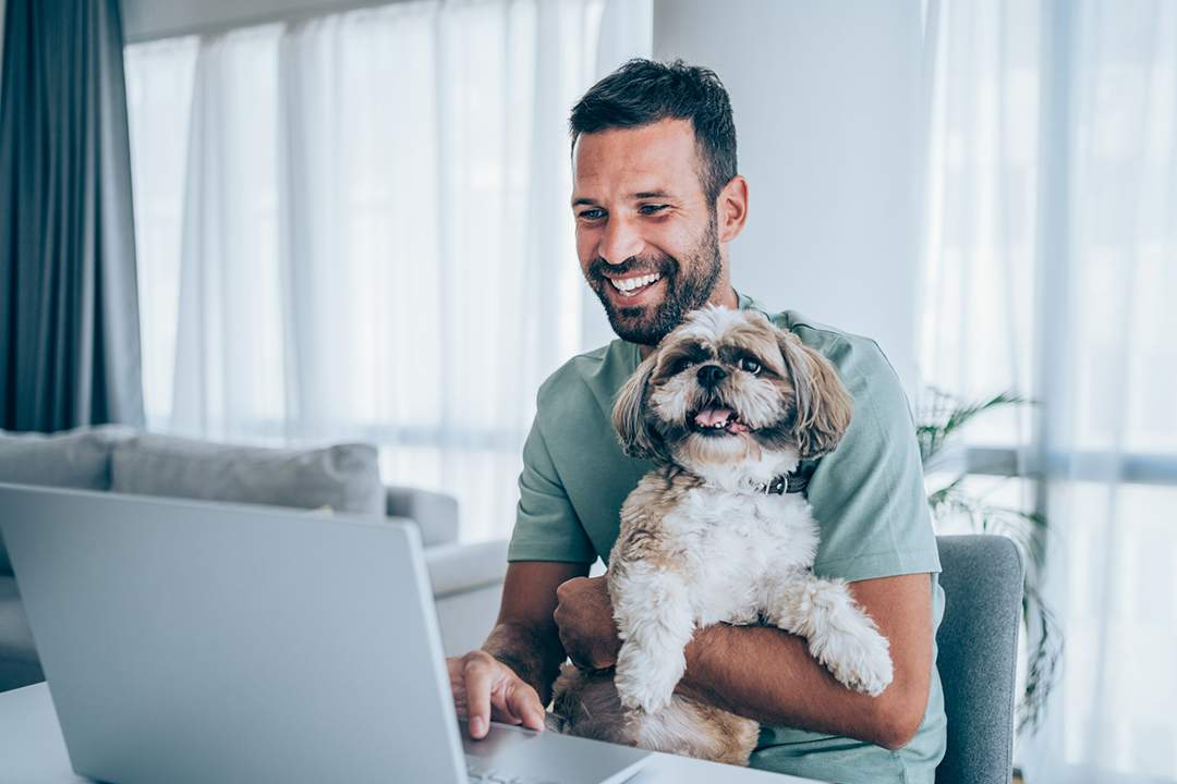 man at a computer holding a dog